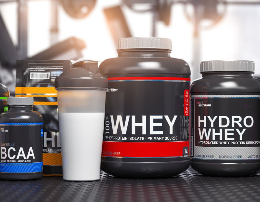 Lactose free bodybuilding supplements including whey protein isolate, hydro whey, and BCAA capsules displayed with protein shaker in gym setting